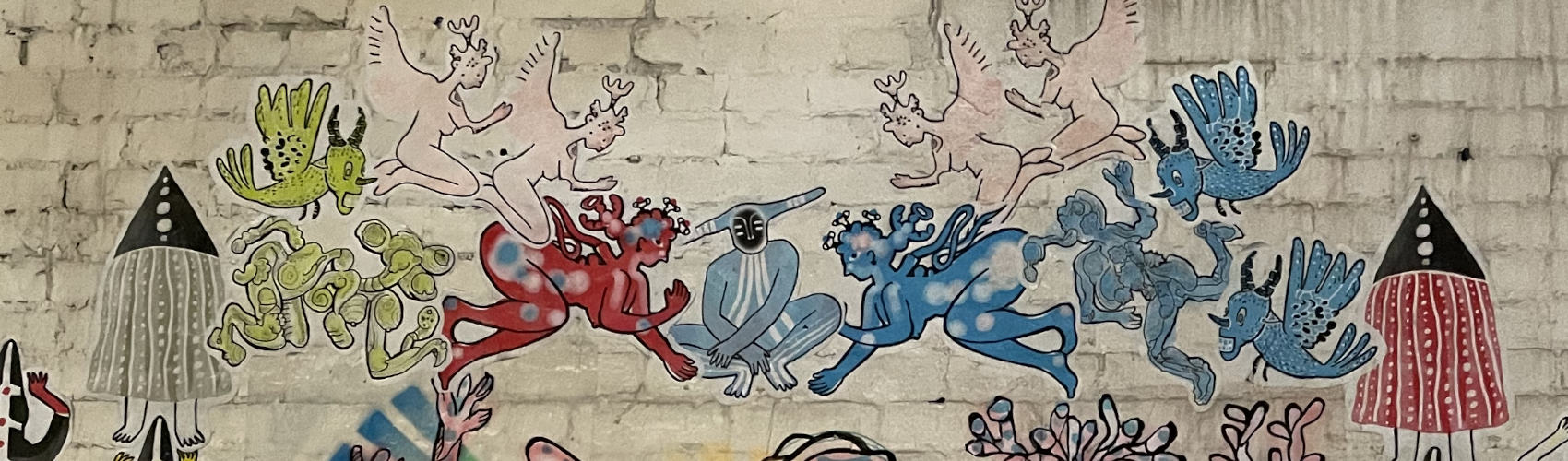 Colorful devils and angels and other mysterious creatures in a fragment of a mural painted on a white brick wall. From photo of a mural signed by Dominica Harris. I took the photo in New York City in September 2023.